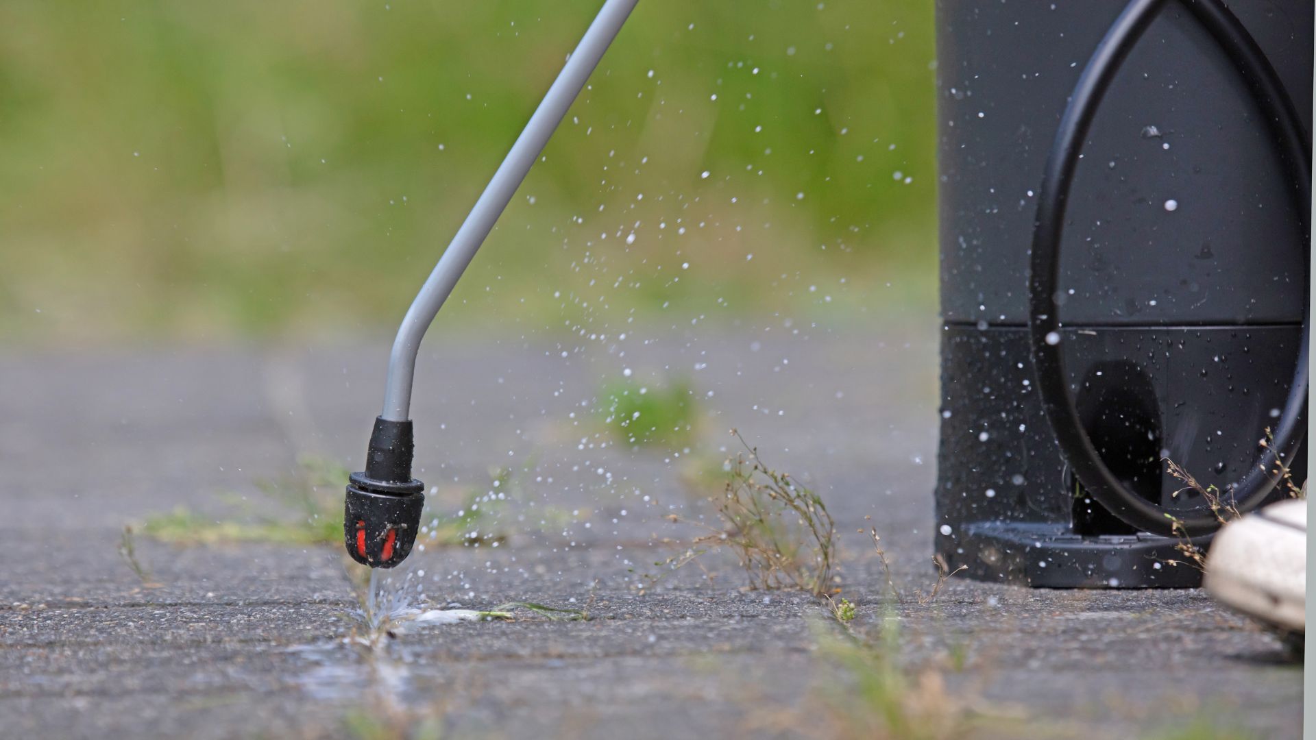 Water spraying from a pressure washer nozzle on concrete ground