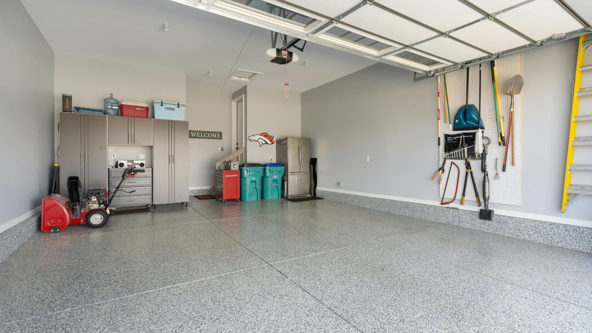 Clean, organized garage with storage cabinets, tools, and Denver Broncos decor
